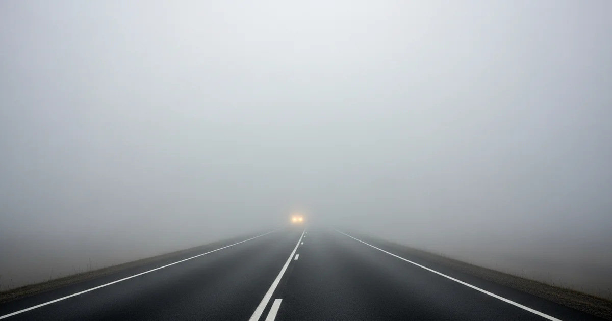 Dense fog blankets a roadway, creating hazardous driving conditions and reducing visibility for motorists. Dense fog blankets a roadway, creating hazardous driving conditions and reducing visibility for motorists.