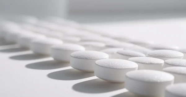 Close-up of white pills arranged in rows.