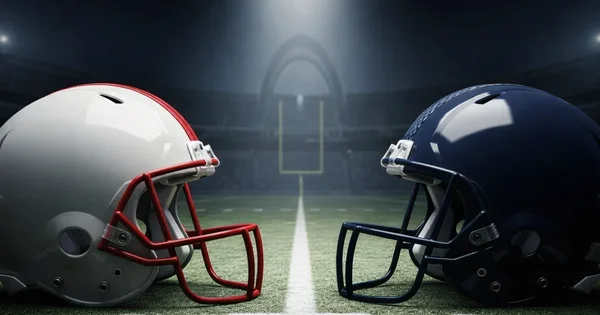 Two football helmets face each other on a field.