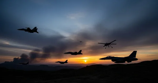Multiple military aircraft fly over a landscape at sunset.
