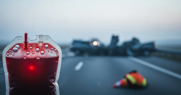 A blood bag is shown against the backdrop of a highway collision, highlighting the ongoing need for life-saving donations in emergency situations.