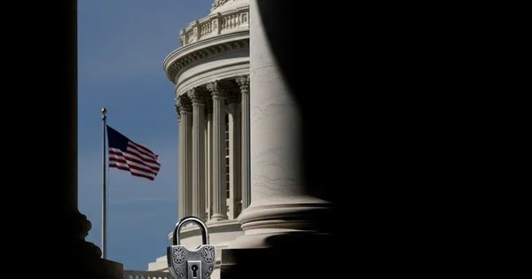 The image shows a padlock in the foreground with the U.S. Capitol Building and an American flag in the background.
