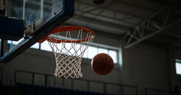 A basketball flies toward a hoop in a gymnasium.