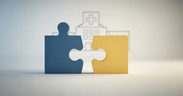 Two puzzle pieces, one blue and one yellow, are about to connect, with a drawing of a hospital in the background.